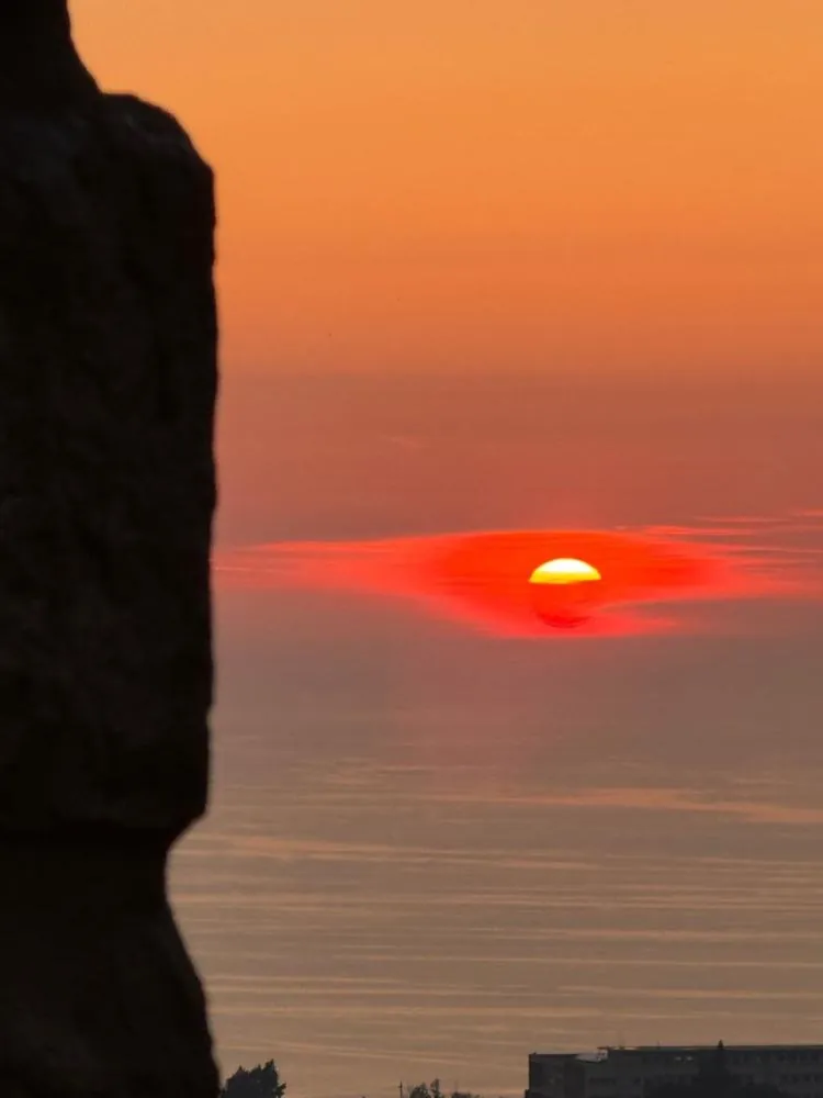 The sun setting over the Mediterranean, seen past the edge of an old stone wall at Qasr Noun